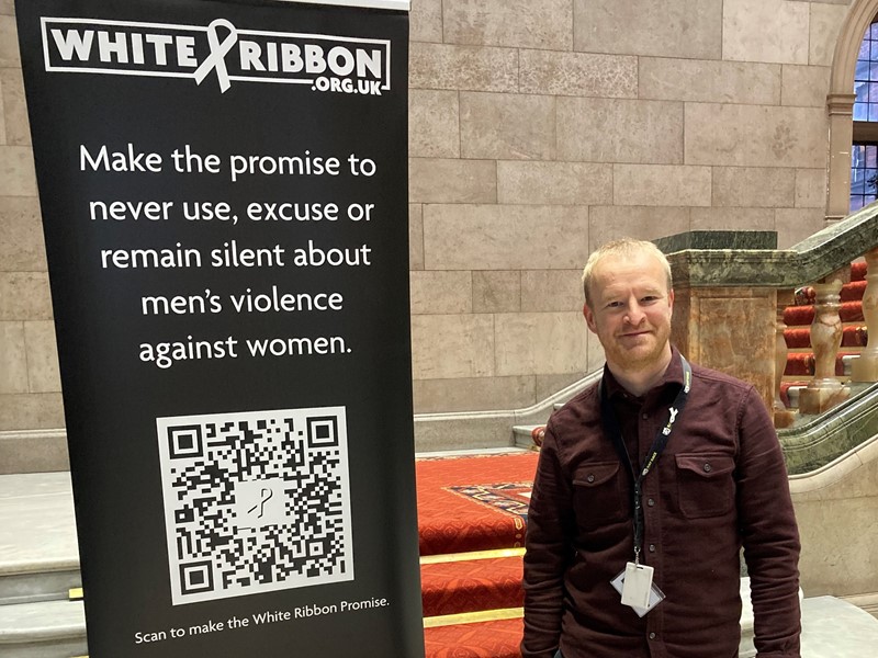 White Ribbon banner in town hall with Tom Smith standing next to it