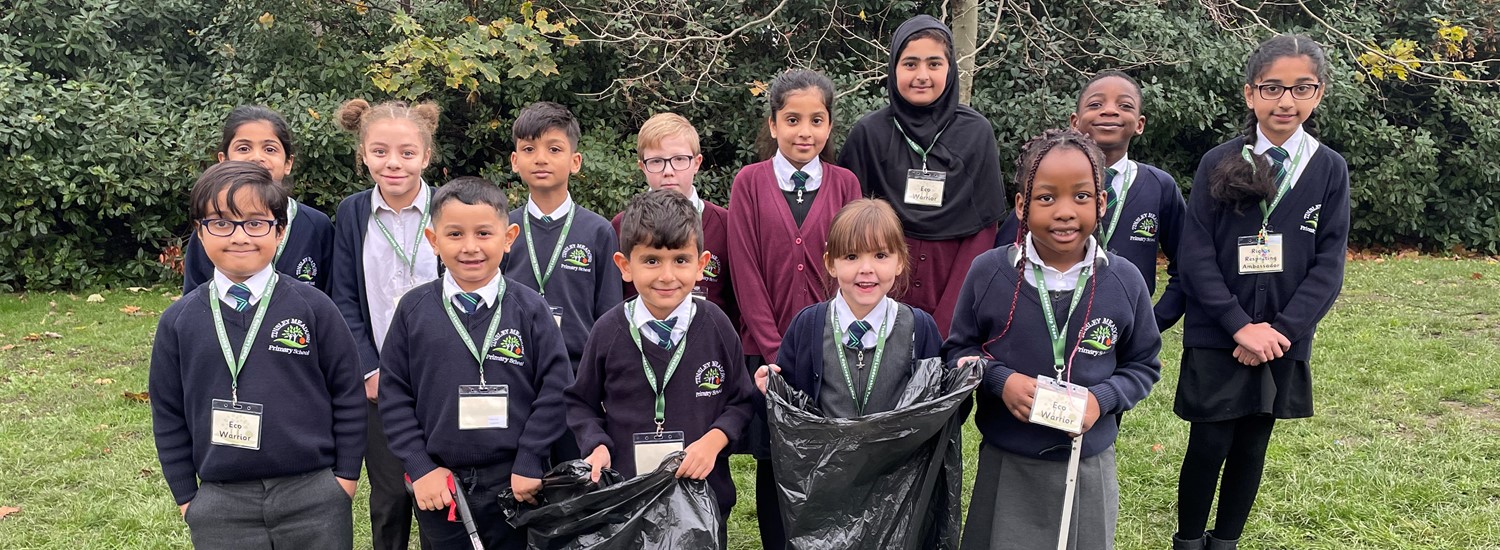 School children stand in group, some with bags and litter pickers