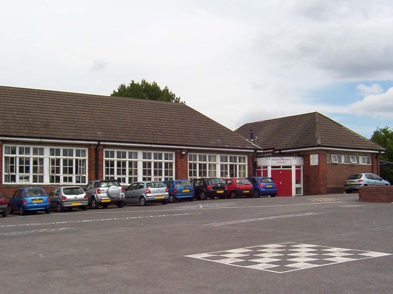 Pipworth School buildings with cars parked outside in the car park 