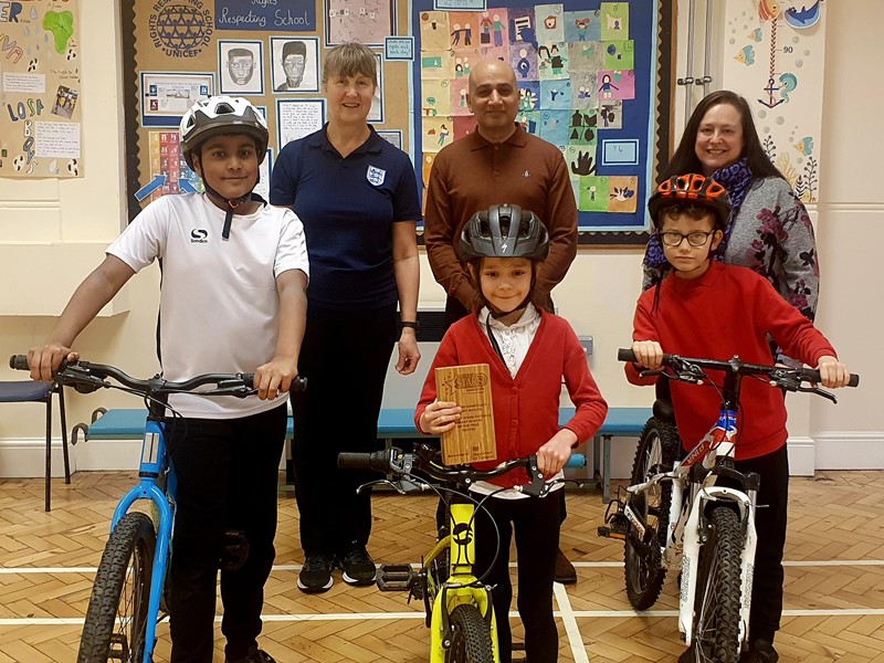 Two teachers and Cllr Mazher Iqbal with 3 pupils and their bikes in a school hall