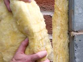 Cavity wall insulation, a pair of hands putting it against a brick wall