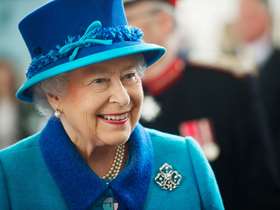 Her Majesty Queen Elizabeth ll smiling in blue coat with darker blue collar and matching hat