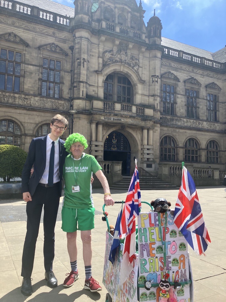 Councillor Tom Hunt and John Burkhill wearing his green wig, and pushing his pram, outside Sheffield Town Hall