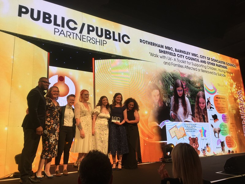 Public/Public Partnership banner and 7 people grouped together holding an award on stage - photo credit Local Government Chronicle