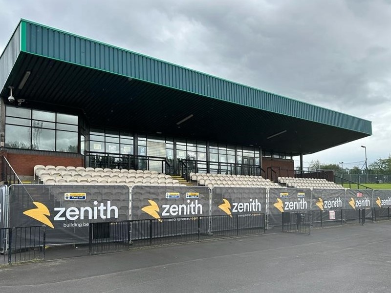 Three sections of seating undercover with glass spectator boxes at the rear