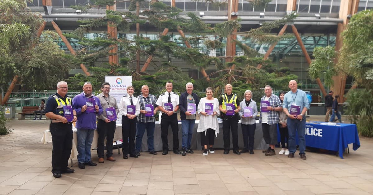 A group of people stand in a line in the Winter Garden in Sheffield, they are holding copies of the new business guide.