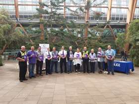 A group of people stand in a line in the Winter Garden in Sheffield, they are holding copies of the new business guide.