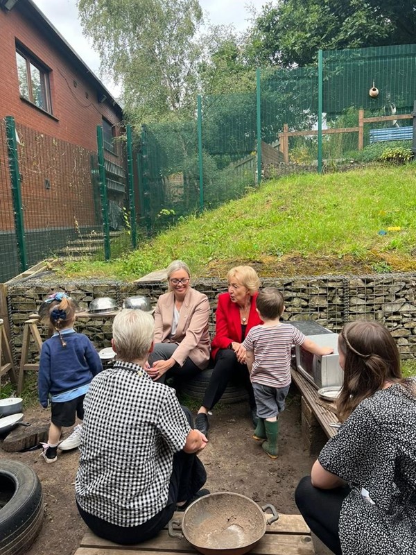 Dame Andrea Leadsom, CEX Kate Josephs and parents and children sat in the garden