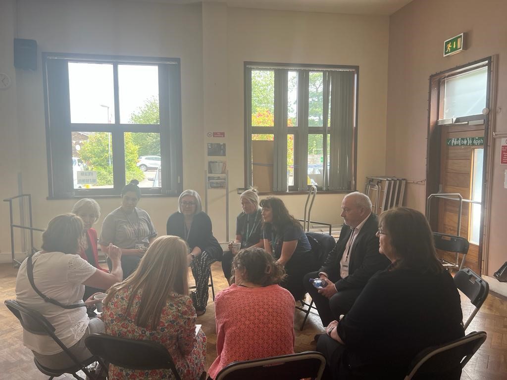 Group of people sat in a circle in a family hub centre having a discussion