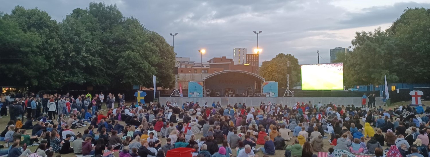 England fans sit on Devonshire Green watching a football match on the big screen