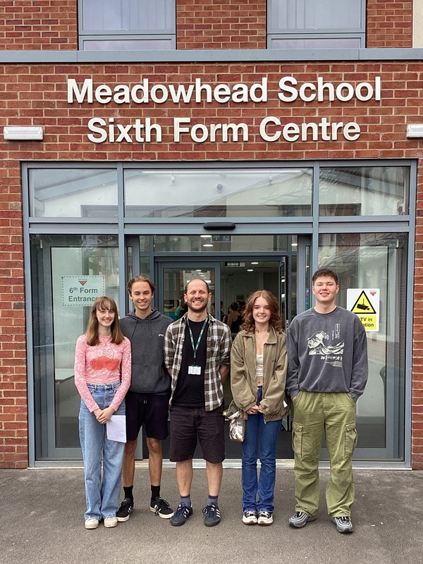 4 A level students and one teacher stand outside the main entrance of Meadowhead School. Sign on wall says 'Meadowhead School Sixth Form Centre'