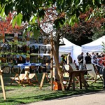 Visitors enjoying the different artwork displayed at Art in the Gardens, among a scenic background of trees