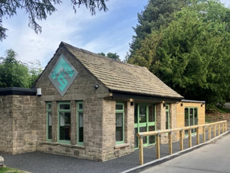 Stone building amongst trees with The Shelter written on the side 