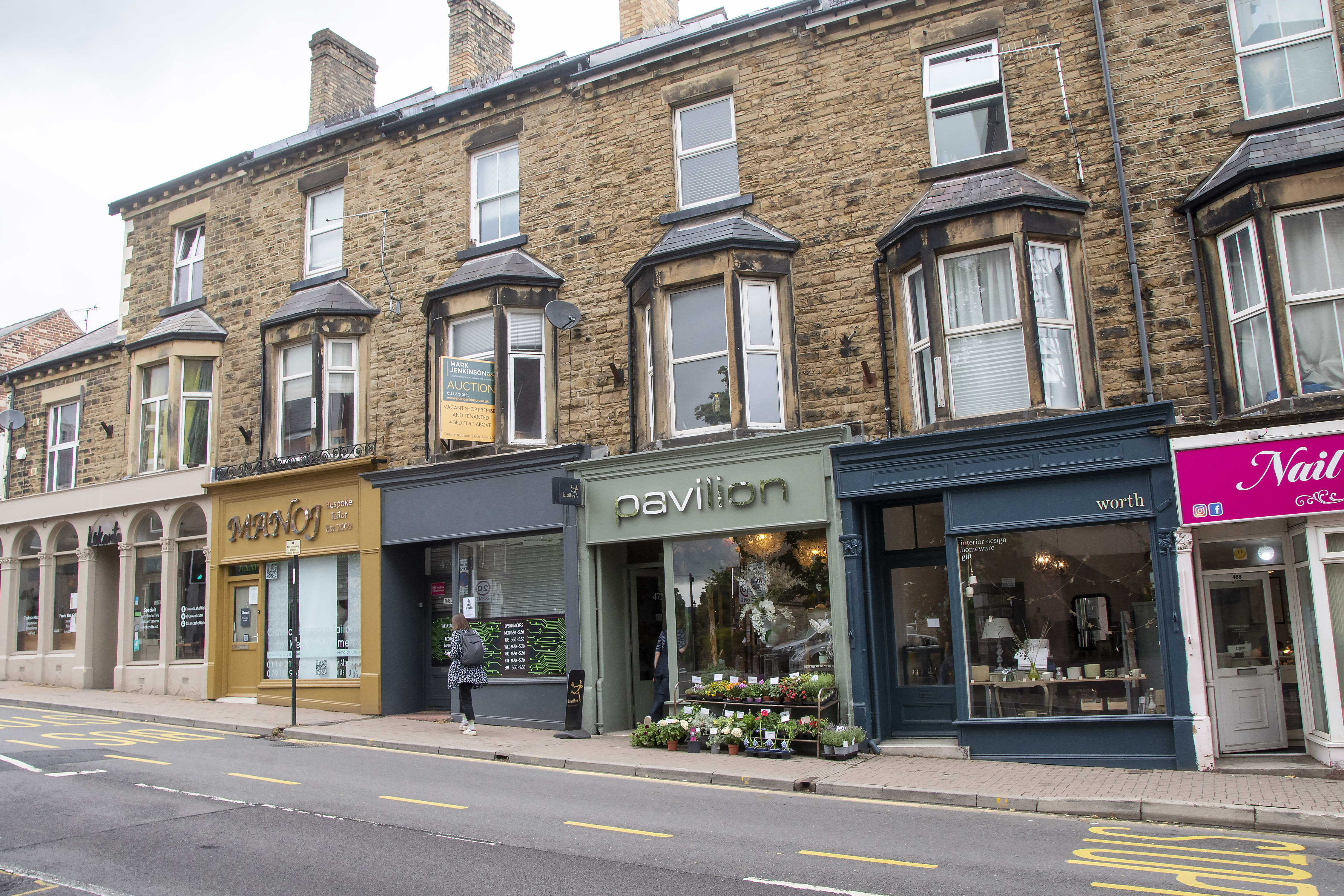 A row of shops with flats above. The shopfronts are newly painted.