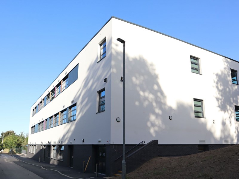 White building with rows of windows overlooking a driveway with blue skies