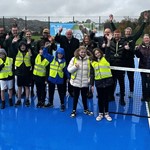 Schoolchildren in front row on tennis court in yellow hi-vis with SCC officers, Councillor Richard Williams, Friends of Hollinsend Park and LTA officers 