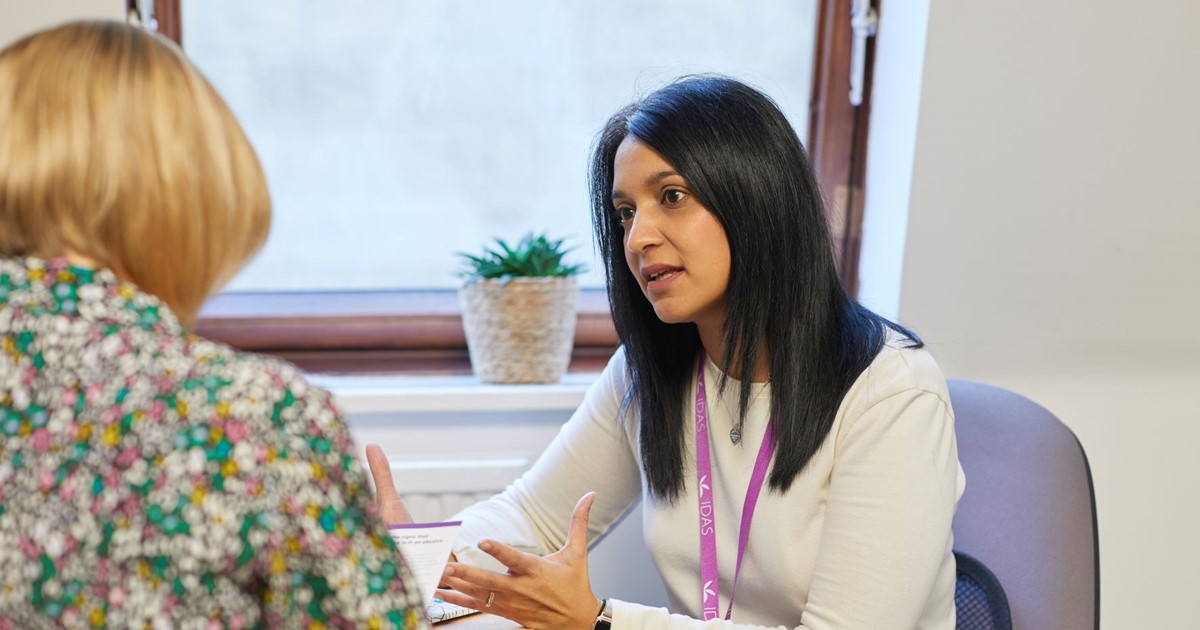 Noreen, Community Team Manager at IDAS Sheffield, speaking to another person at a desk.