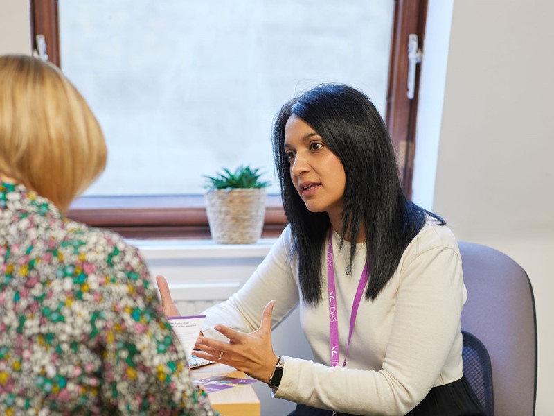 Noreen, Community Team Manager at IDAS Sheffield, speaking to another person at a desk.