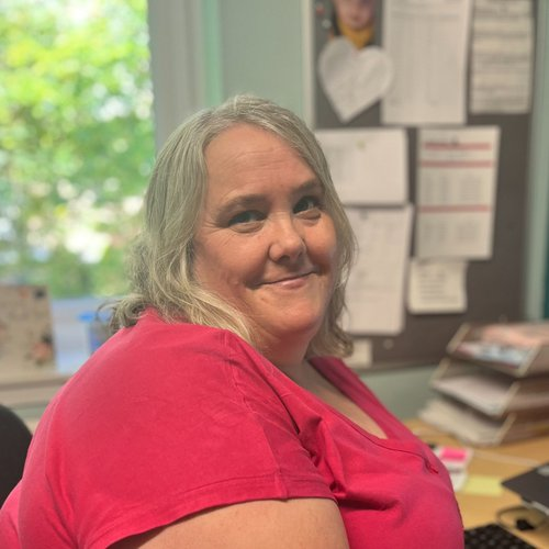 Janet, Head of Operations at Sheffield Women’s Aid, sitting at an office desk and smiling.