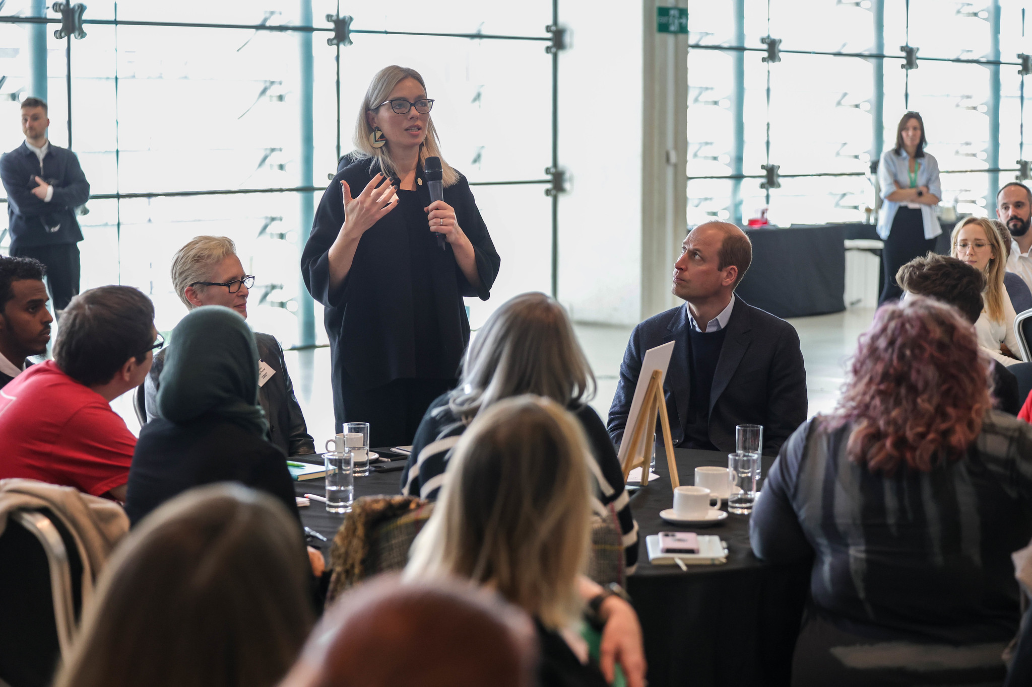 Chief Executive of Sheffield City Council Kate Josephs speaks into a microphone at a Homewards event in Sheffield's Millennium Gallery while attendees including HRH The Prince of Wales listen
