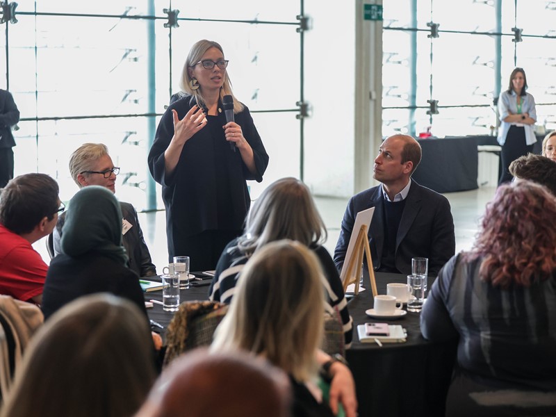 Chief Executive of Sheffield City Council Kate Josephs speaks into a microphone at a Homewards event in Sheffield's Millennium Gallery while attendees including HRH The Prince of Wales listen