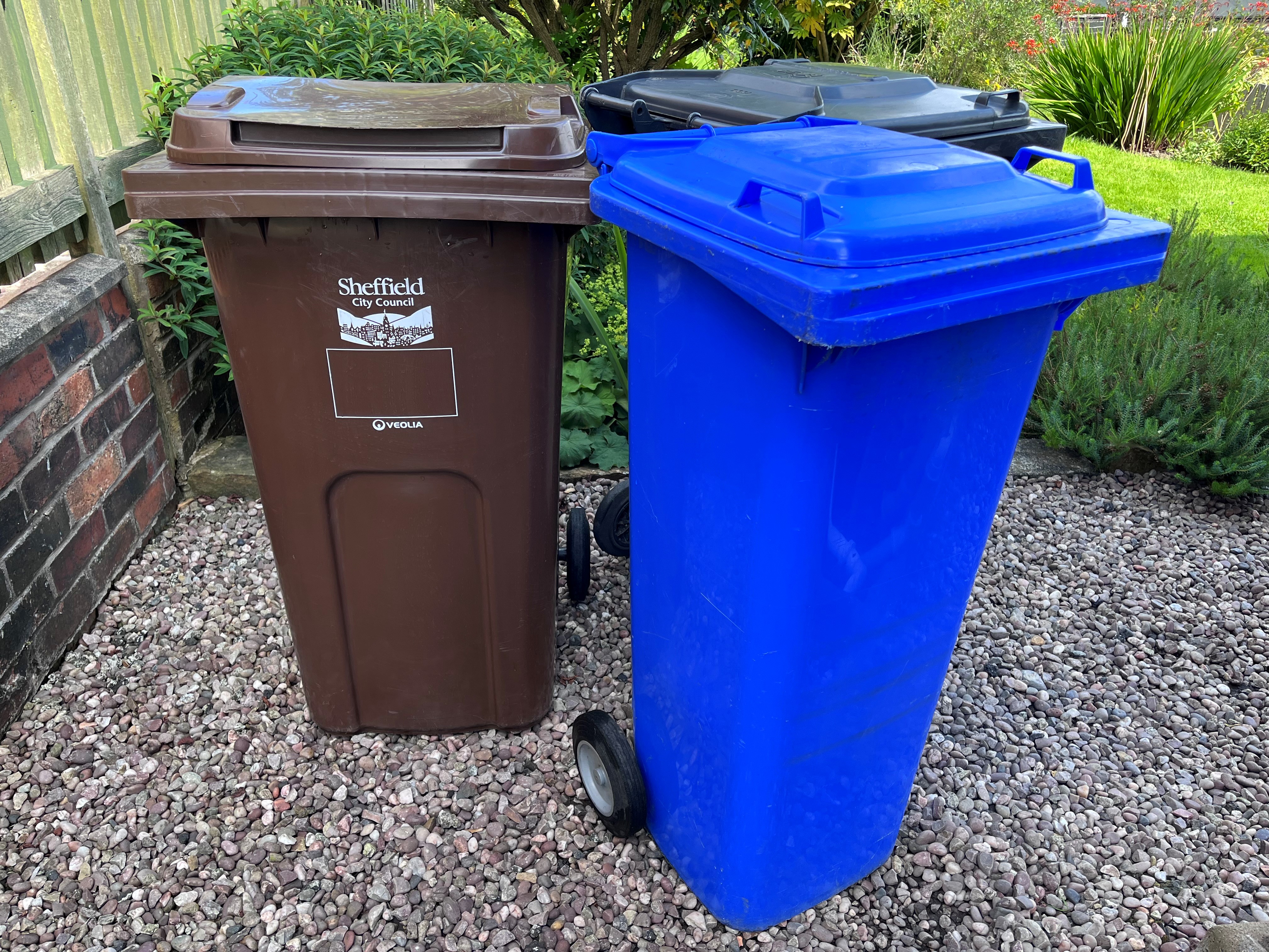 Blue, brown, and black bin in a garden
