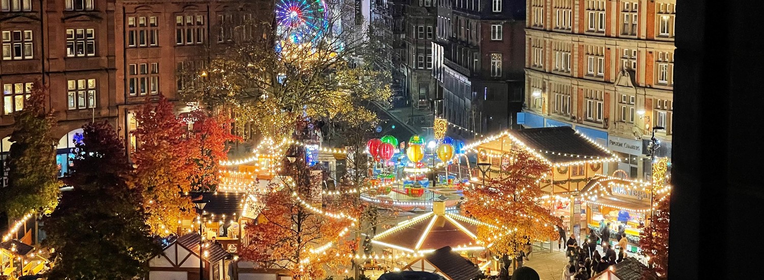 Market stalls all lit up in Christmas lights in amongst city centre buildings