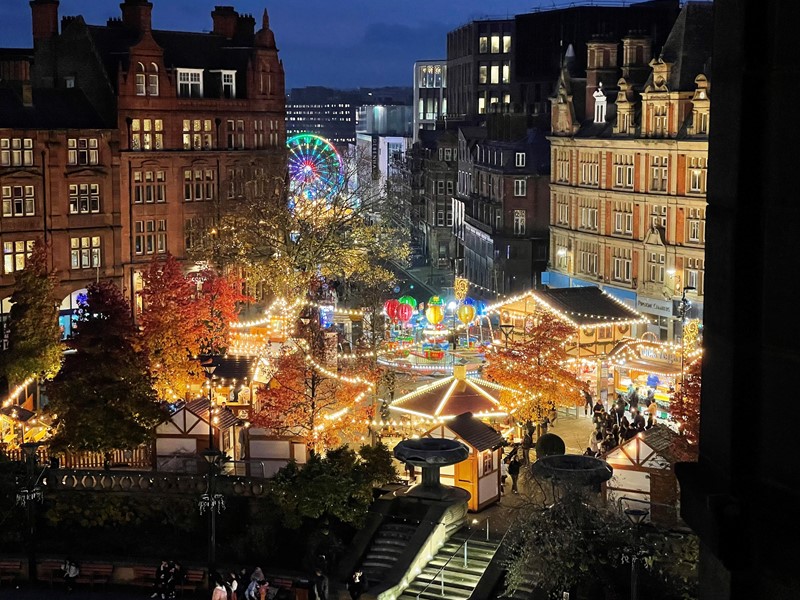 Market stalls all lit up in Christmas lights in amongst city centre buildings