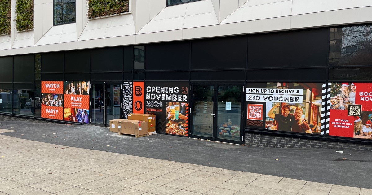 The front of the unit in the Gaumont building showing the black frontage with colourful posters, above are windows with white surrounds and plants in between.