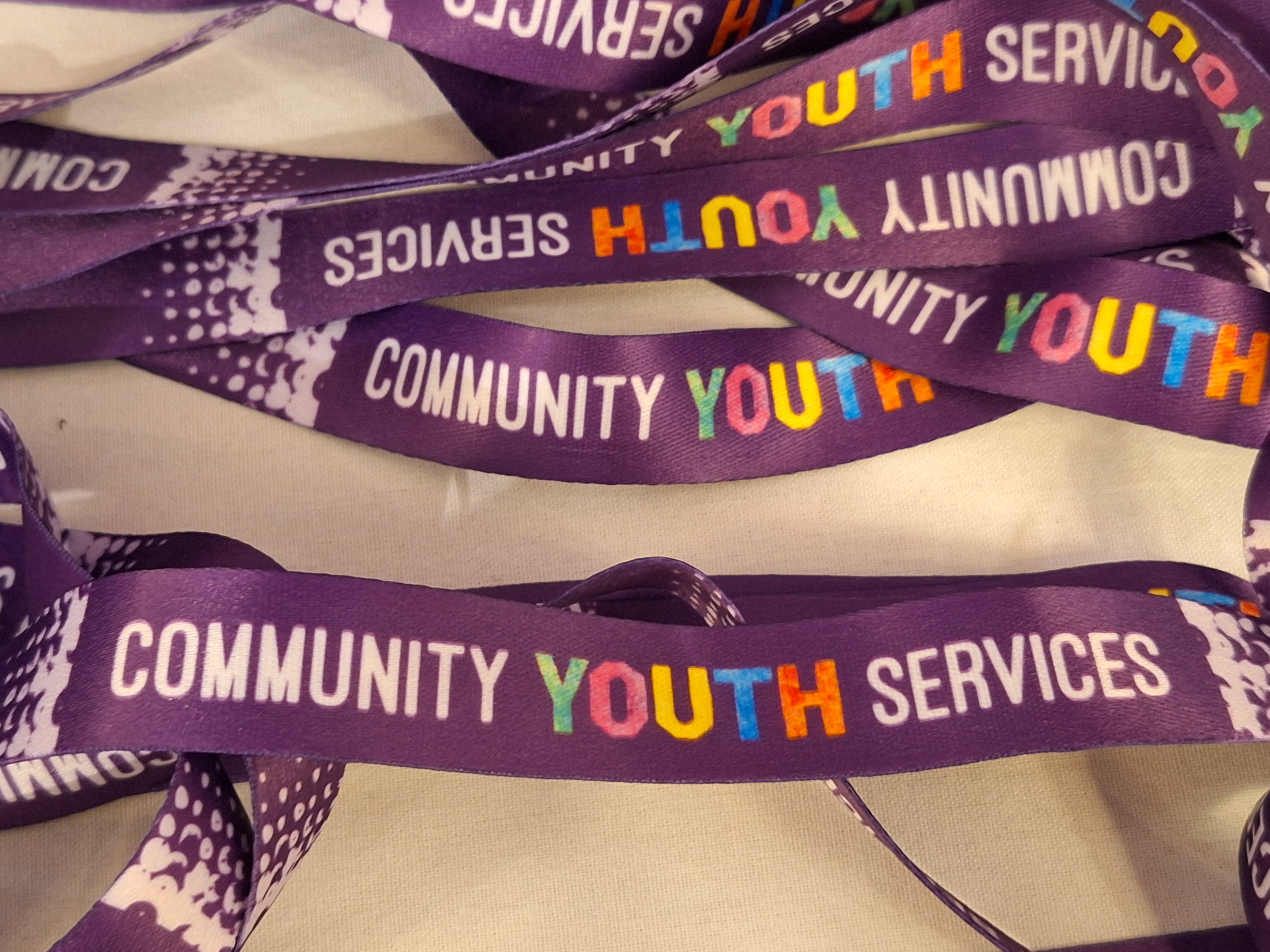 Purple silk lanyards with Community Youth Services written across them 