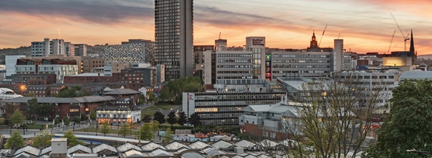 View of Sheffield with buildings lit up. An orange and blue sky in the background.