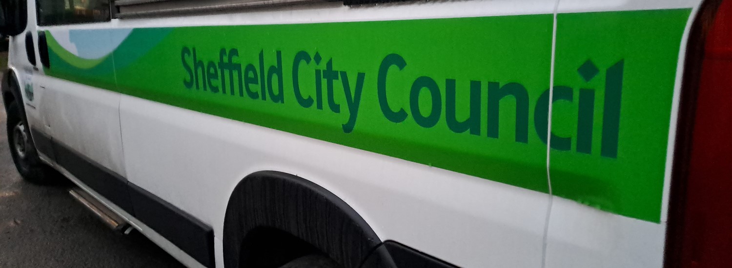 The side of a white minibus with green Sheffield City Council branding down the side
