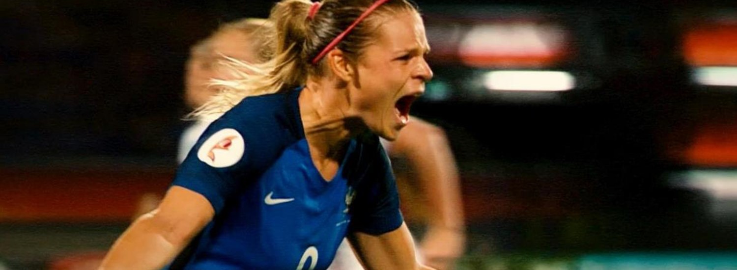 woman footballer in dark blue kit celebrating