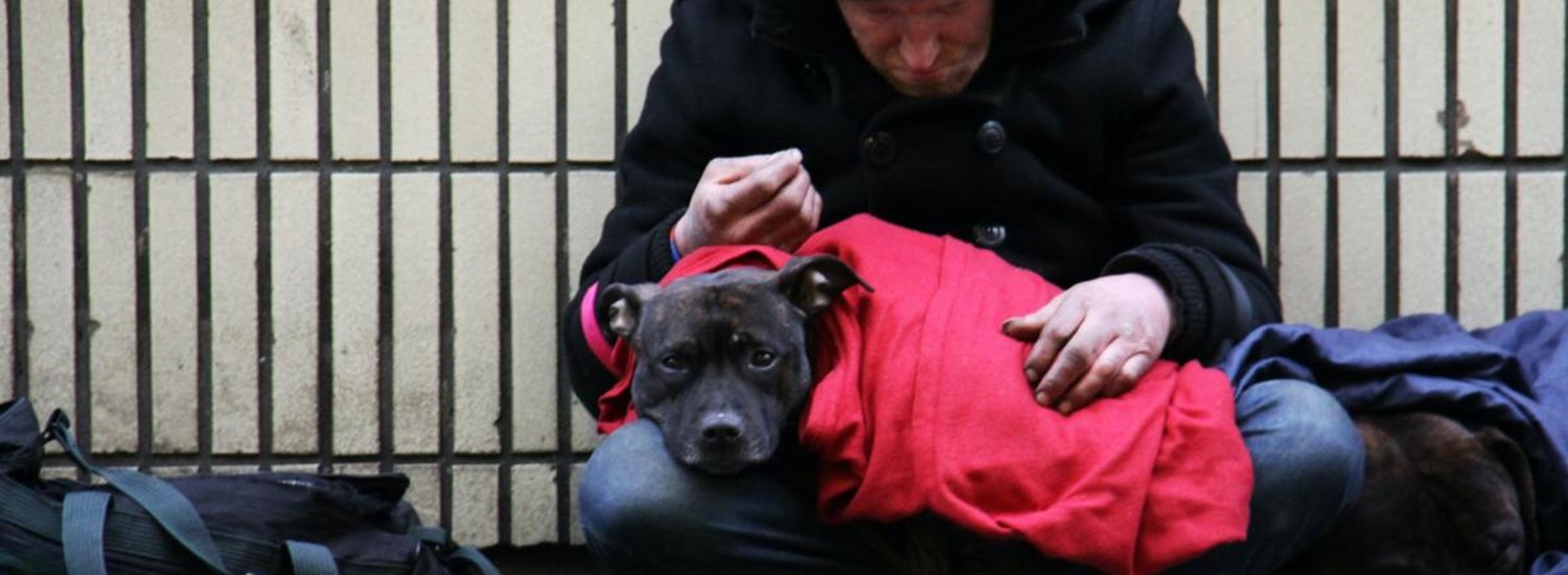 A rough sleeper huddles on a path with his dog