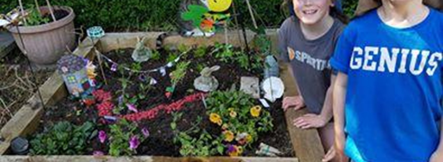 Two boys stand next to a fairy garden they have made