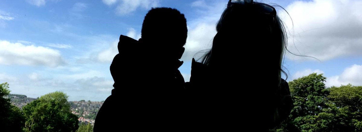 Photograph of an adult holding a toddler in a park