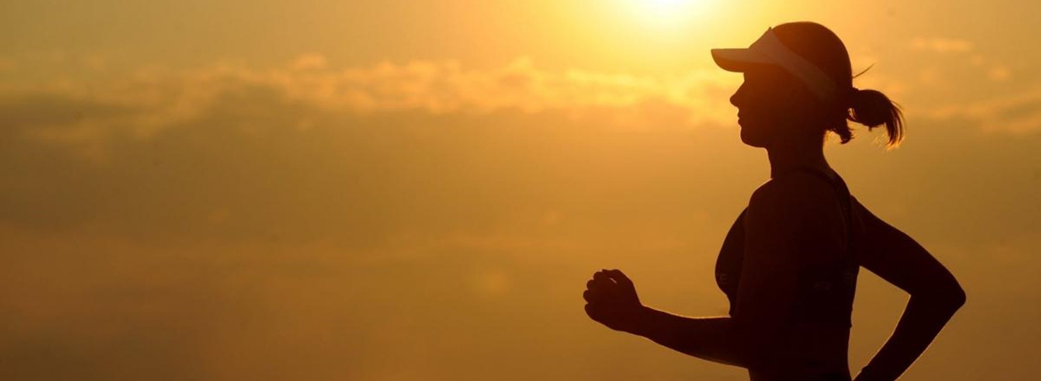 Silhouette of lady running against a sunset