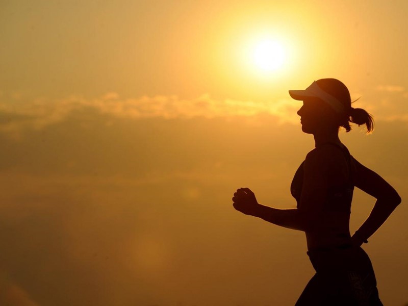 Silhouette of lady running against a sunset