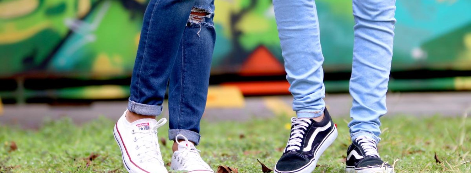 two pairs of teenage legs in jeans and trainers