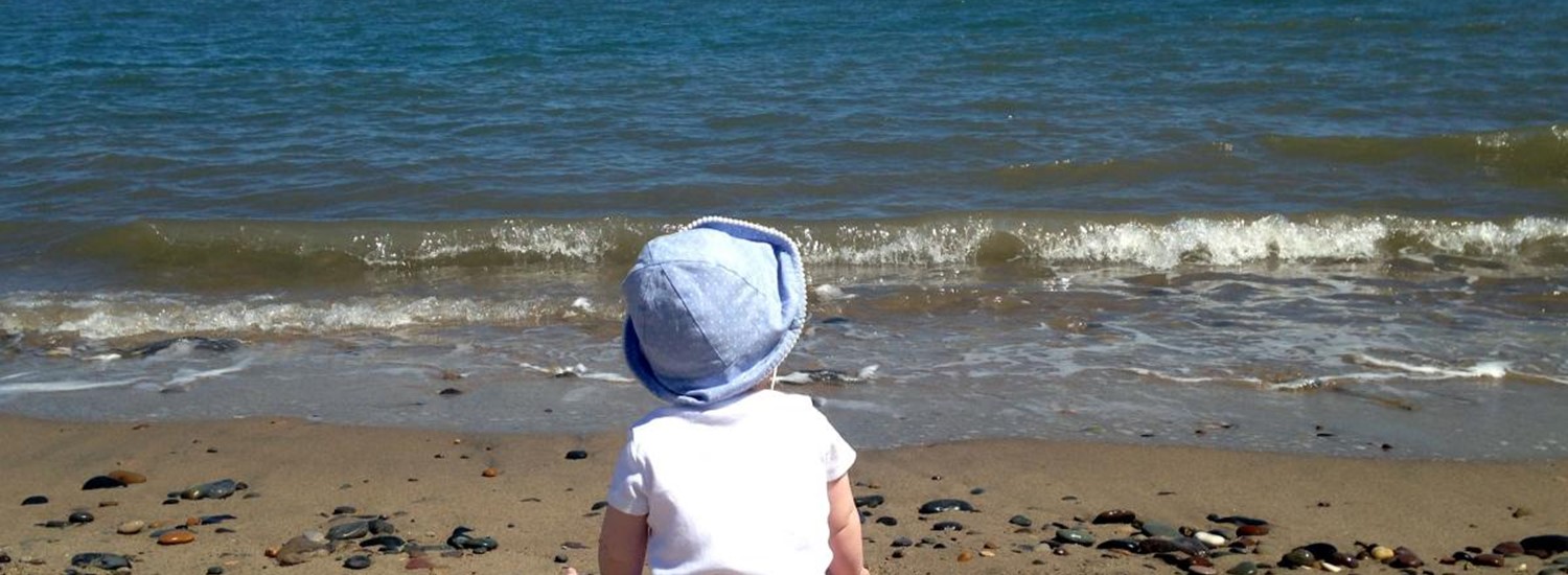 young child sat on the beach