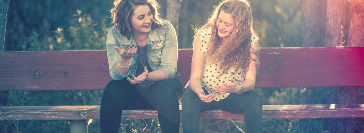 two people sat chatting on a bench