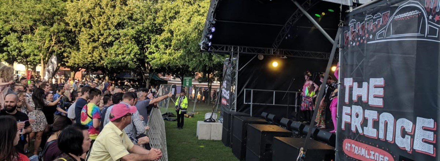 crowd of people looking up at a stage with trees in the background