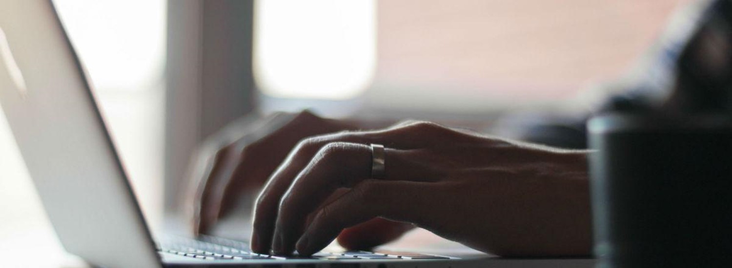 Image of hands typing at a laptop